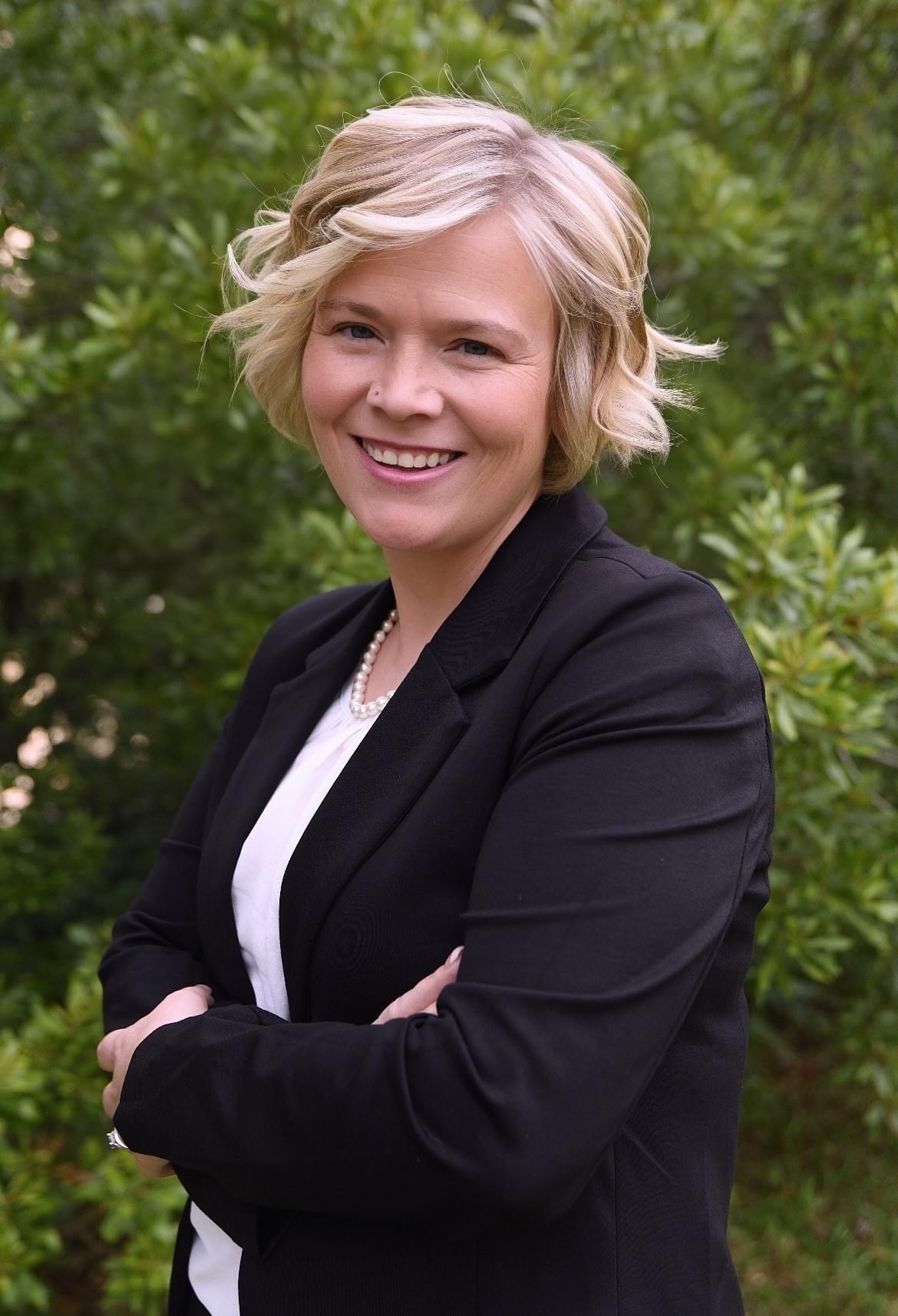 Kacey Carnegie standing in front of plants with her arms folded and smiling at the camera