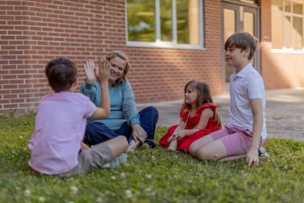 Kacey Carnegie high fiving with school children seated on the grass
